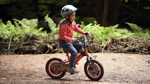 A little boy cycling a bike in the woods